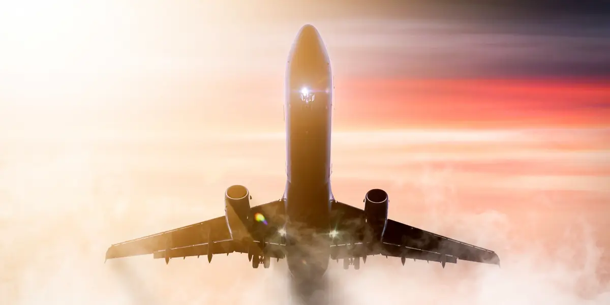 Aircraft flying through sunset and clouds