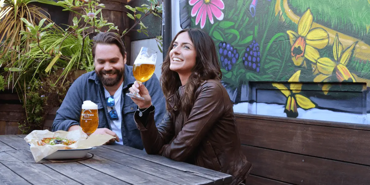 Man and women in pub garden drinking pint of free from beer